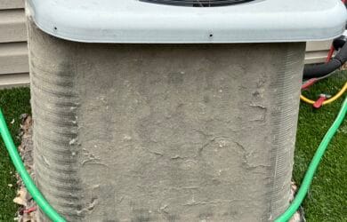 Dirty HVAC condenser unit with debris buildup causing reduced cooling performance